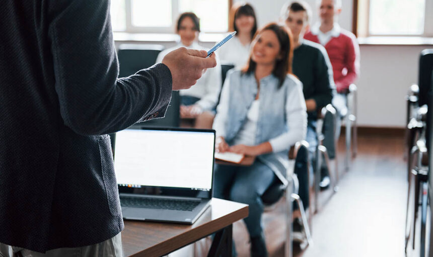 Everyone is smiling and listens. Group of people at business conference in modern classroom at daytime.